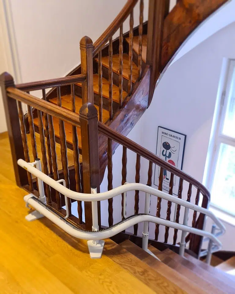 Gebrauchter Kurventreppenlift im Kurvenbereich einer Holztreppe in Emmering